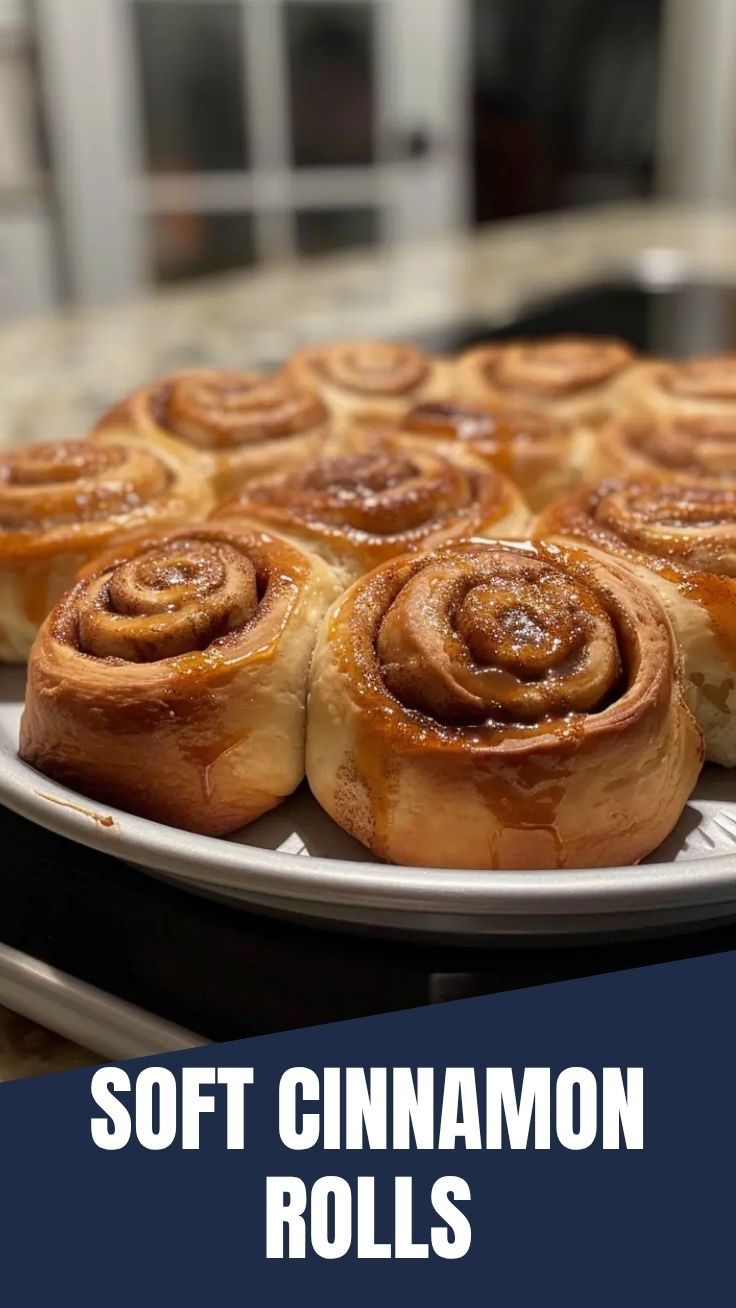 A tray of gooey homemade cinnamon rolls with white icing, fresh from the oven.